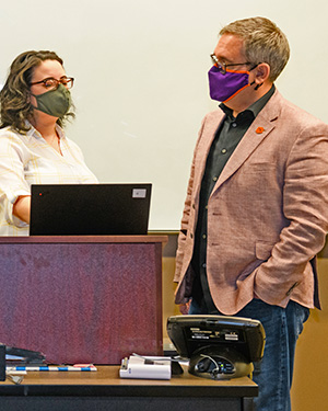 lopes speaks with a graduate student at the front of a classroom