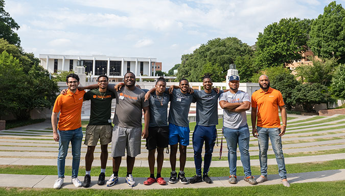 Group of men smiling in front of the amphitheater.