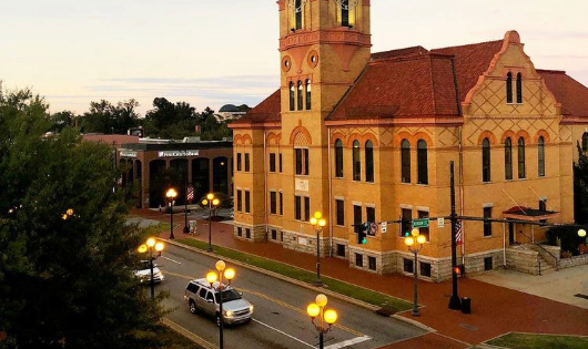 High-angle view of the historic brick Old Anderson County Courthouse at dusk with a car driving on the adjacent street lit by streetlamps.