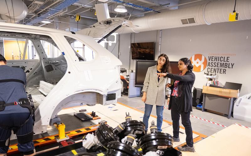 Researchers pointing at an automotive vehicle frame