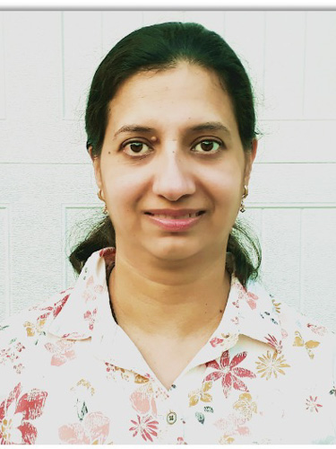 Head-and-shoulders portrait of a woman with dark hair pulled back, wearing a white floral button-up shirt against a light background.