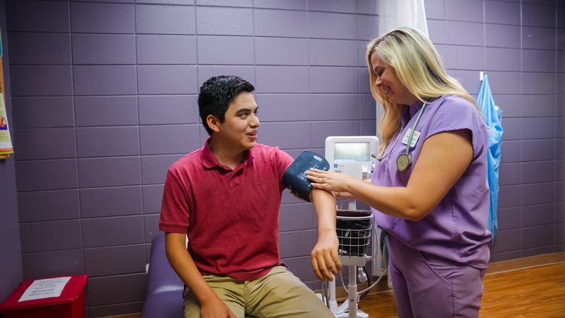 Nurse with a patient checking his blood pressure on campus