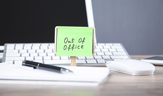 An Out of Office note left on a computer keyboard.