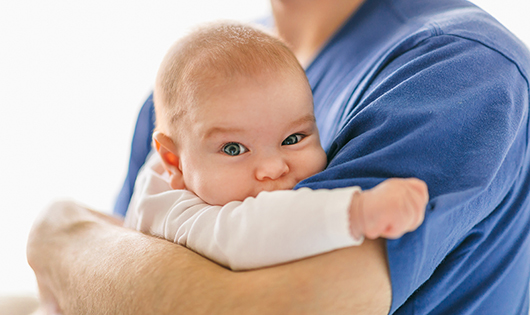 A baby being held by an adult.