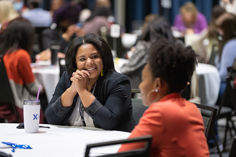 Professionals networking and chatting at a conference reception in a bright, modern atrium.