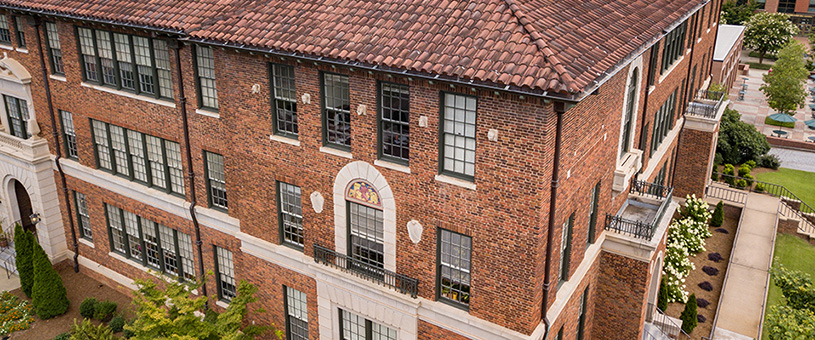 An aerial view of a brick building with a shingled roof.