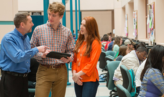 2 Students discussing with a professor in computer lab