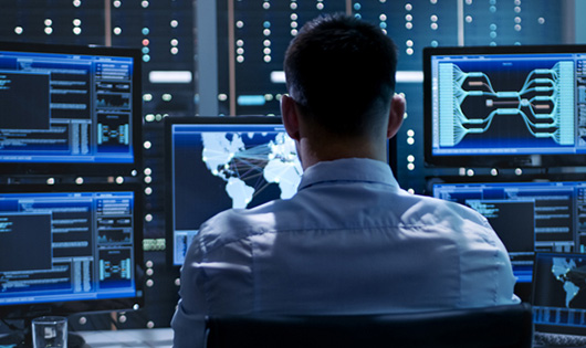 Man looking at 5 computer screens