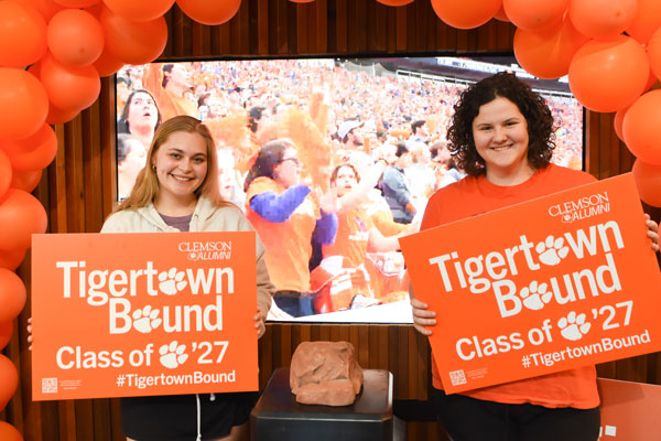 Two female admitted students pose with a replica of howards rock while holding tigertown bound signs