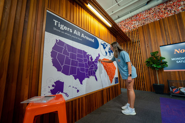 A young woman places a pin on a map of the united states that reads Tigers All Around