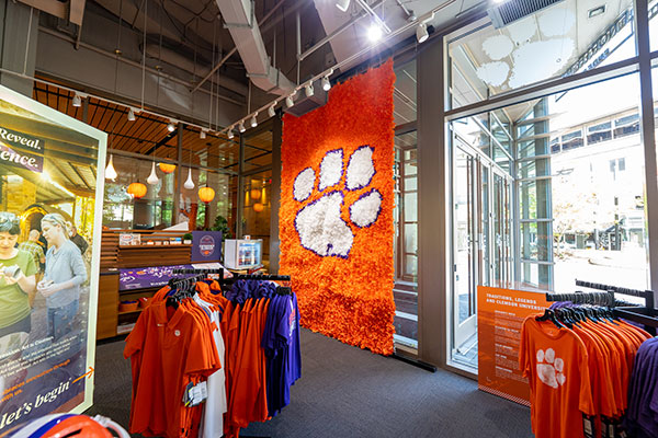 the interior of experience clemson showing clemson merchandise and clothing with a paper mache clemson paw in the background