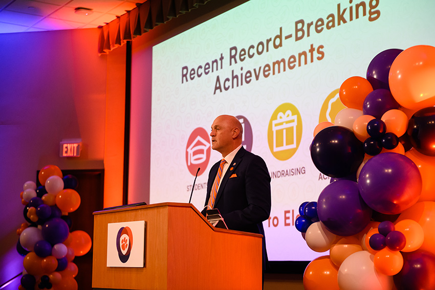  President James P. Clements stands at a podium surrounded by orange and purple balloons as he announces the Clemson Elevate strategic plan. 