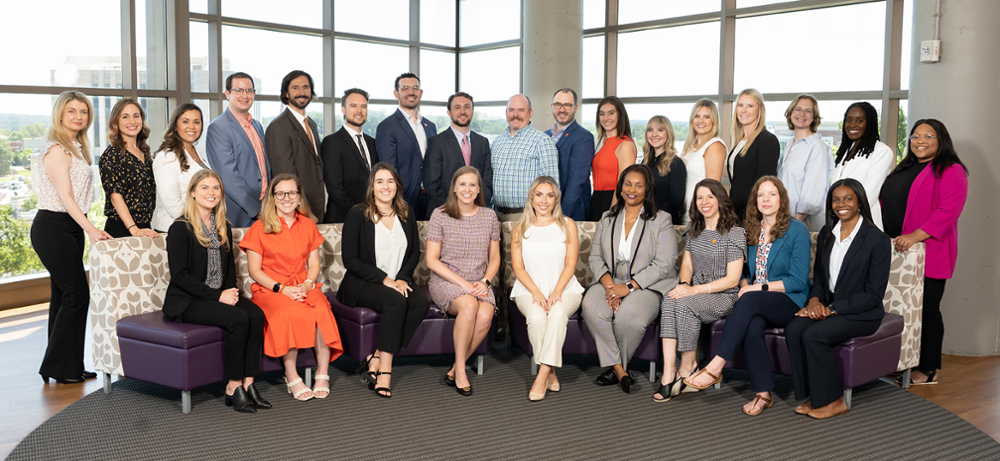 Group photo of a diverse team of professionals posing together in a modern office setting.