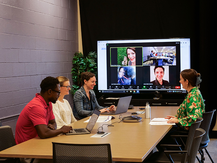 Several members of Clemson Online’s For-Credit Staff meeting in a conference room and on Zoom.