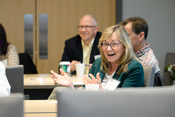 Sitting at round table woman happily smiling at event with other departmental chairs