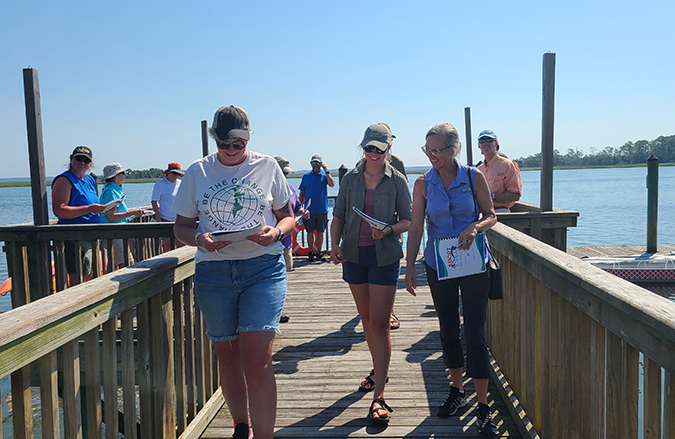 Volunteers smiling on a dock and holding SC Adopt-a-Stream Handbooks during a workshop.
