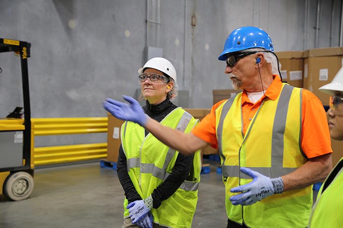 State Team member Katie standing with Nestle representatives wearing hard hats, gloves, and safety glasses as they tour the facility.