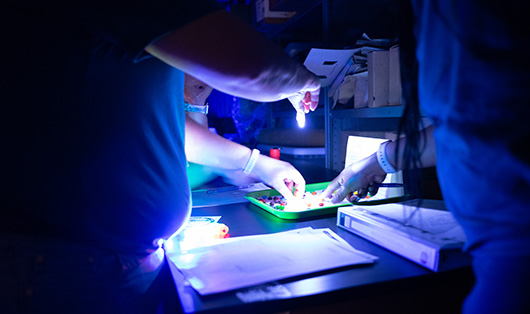 two people in a lab with dim lights doing research