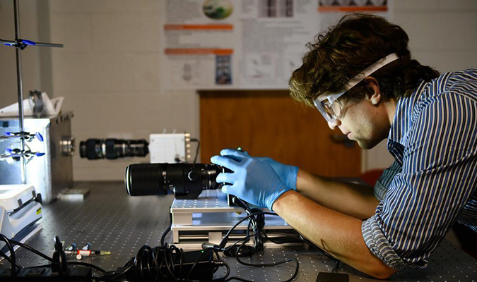 A male researcher wearing safety glasses and gloves in a research lab