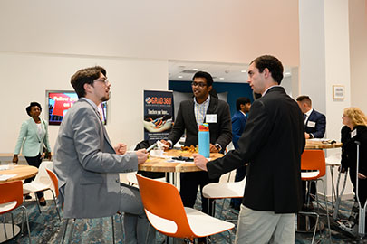 A group of professionals engaging in conversation at a networking event, surrounded by tables and food.