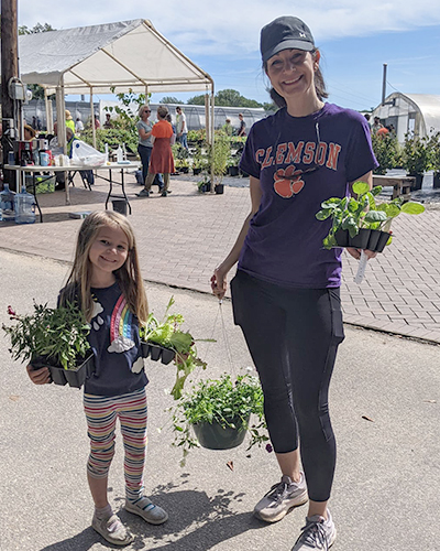 mother and daughter holding plants at a plant sale