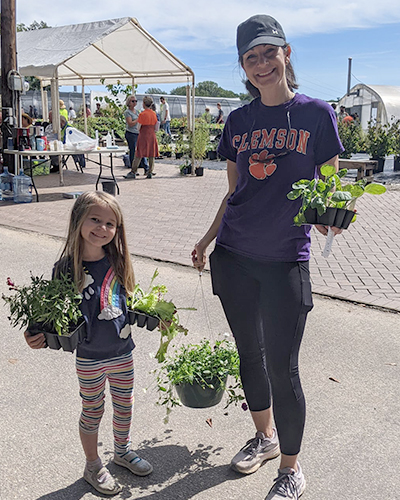 mother and daughter holding potted and hanging plants