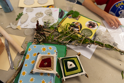 craft table covered with yarn, sticks and scissors during craft project time