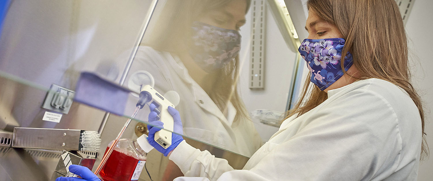 Woman, Jennie Mason, works with red liquid under vent hood in lab.