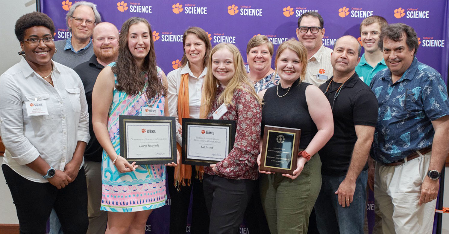 Group of 12 people, some students holding awards, with faculty.