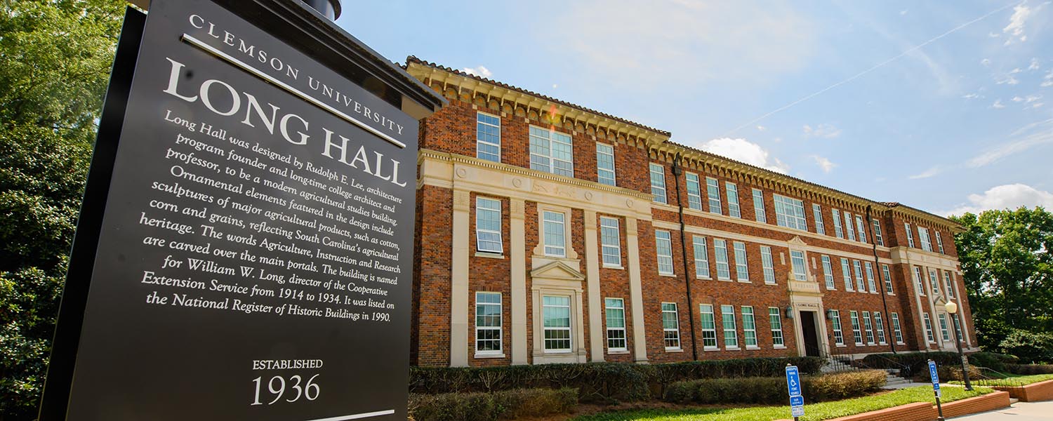 Brick building (Long Hall) on college campus, with historical marker sign.