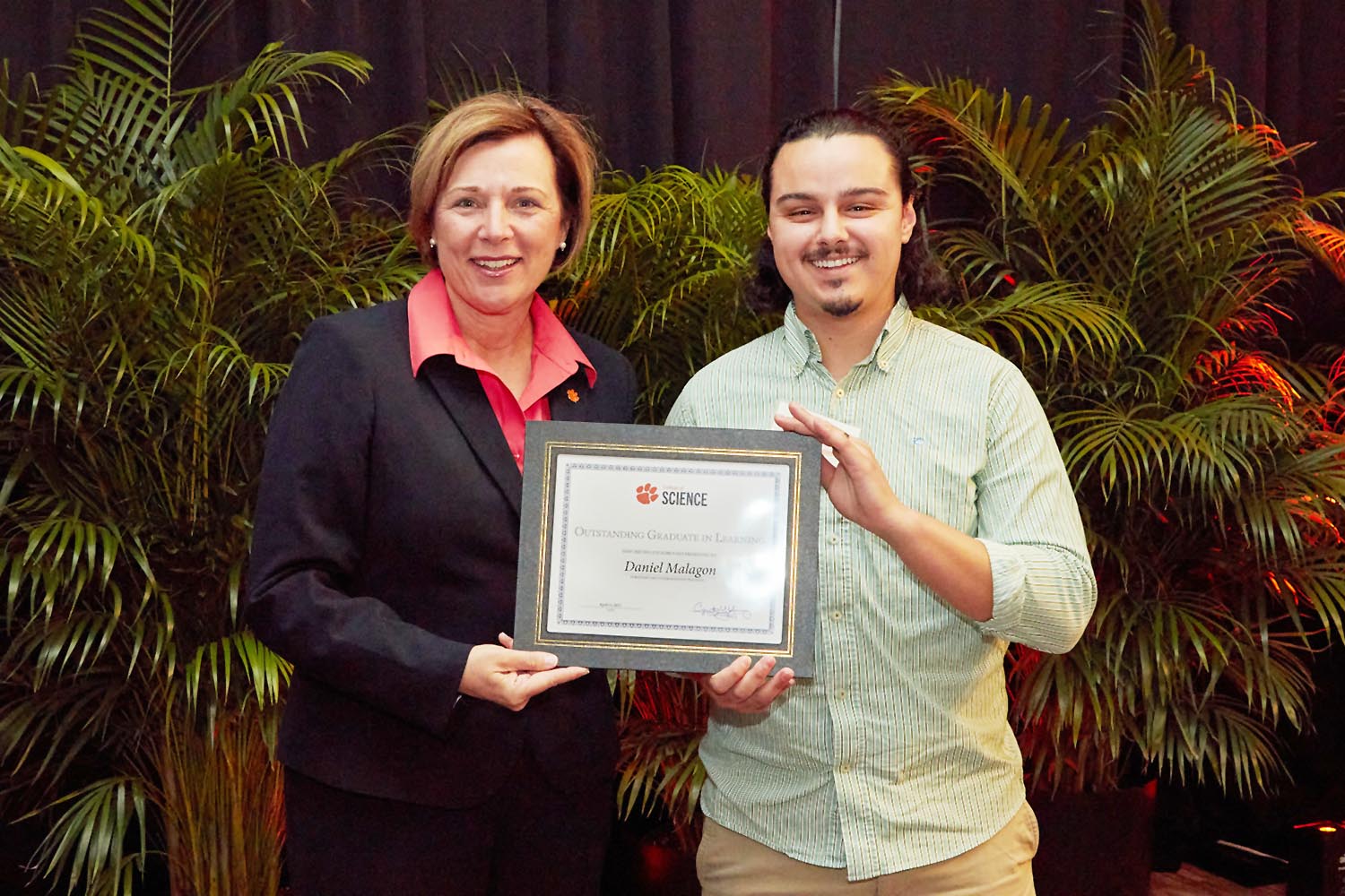 Woman (Cynthia Y. Young) with man (Daniel Malagon), holding award plaque.