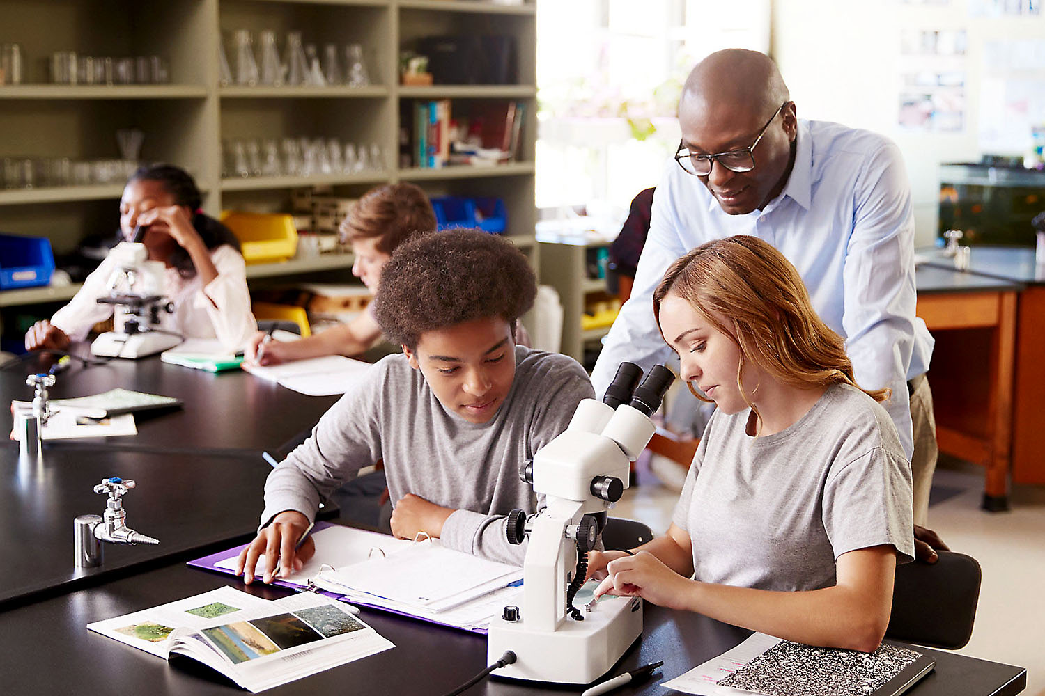 Teacher with two science students, middle or high school.