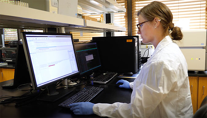 Woman at computer in a lab. Frame from video.