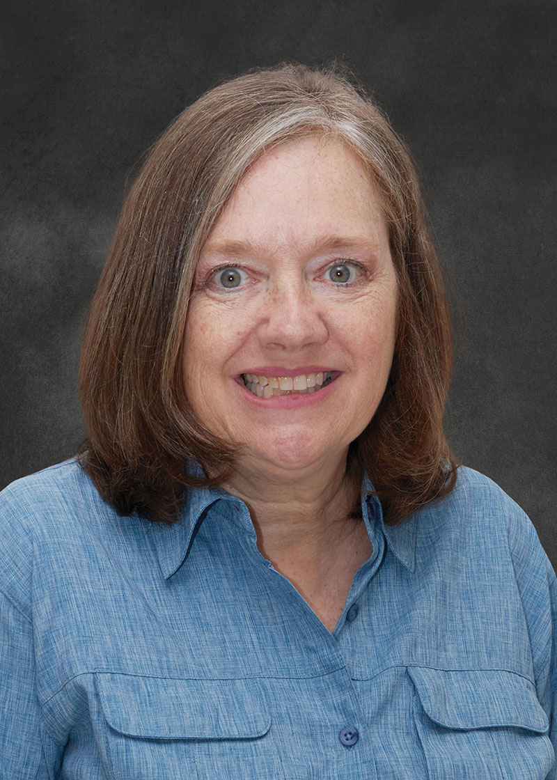 Headshot of woman, Lesly Temesvari, on dark gray background.