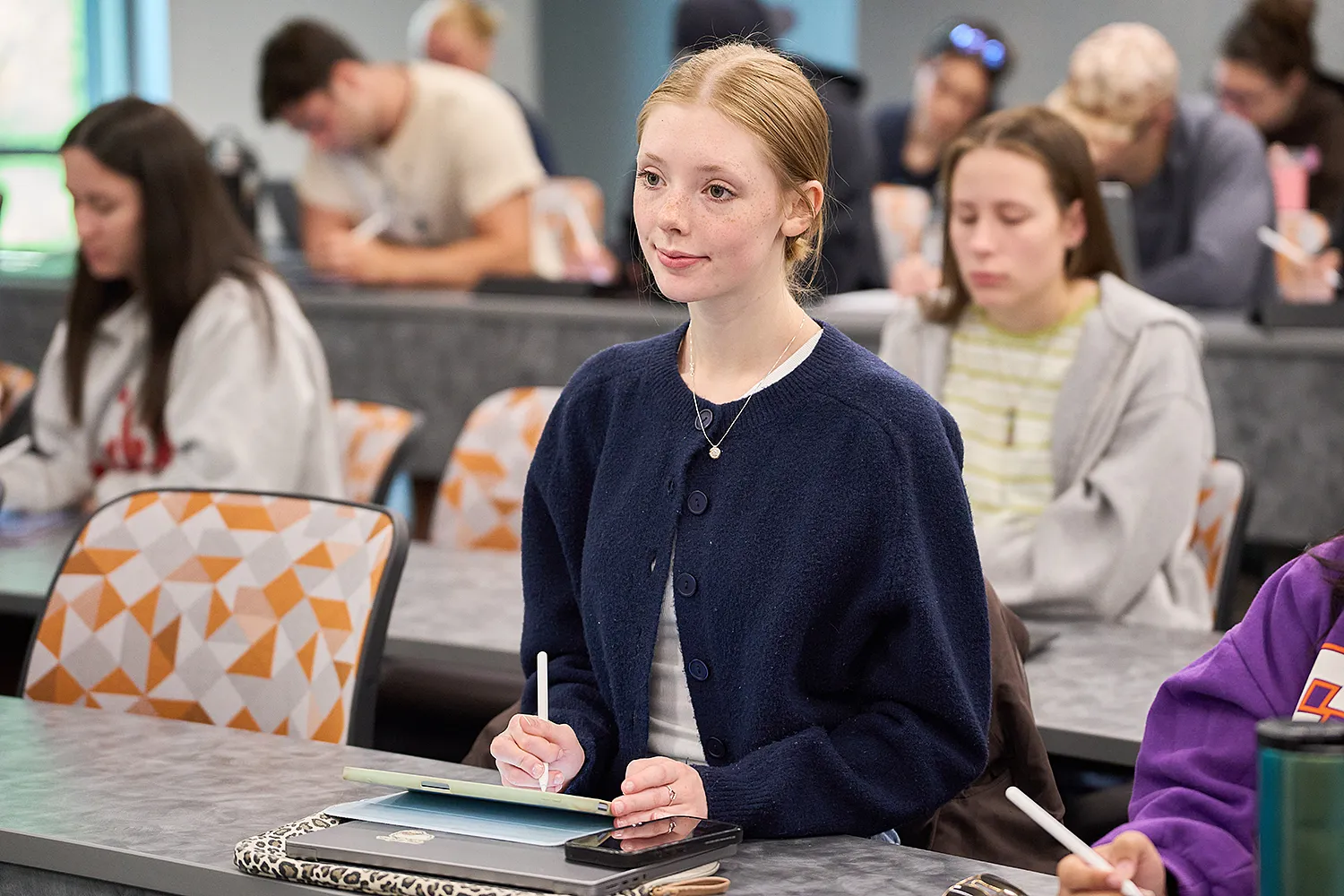 A female student in a large lecture classroom.