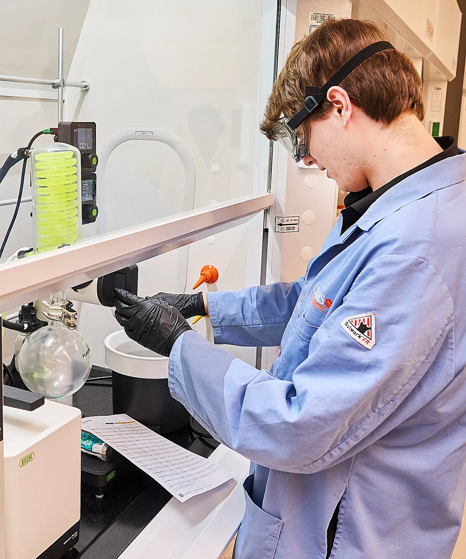 Student wearing a lab coat and gloves working in a lab.