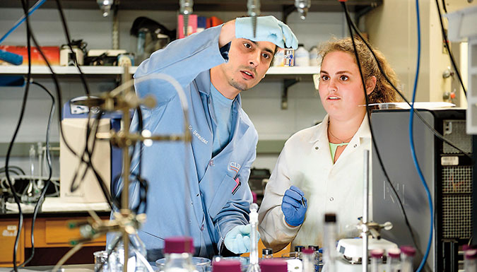 Two students examining a solution in a lab.