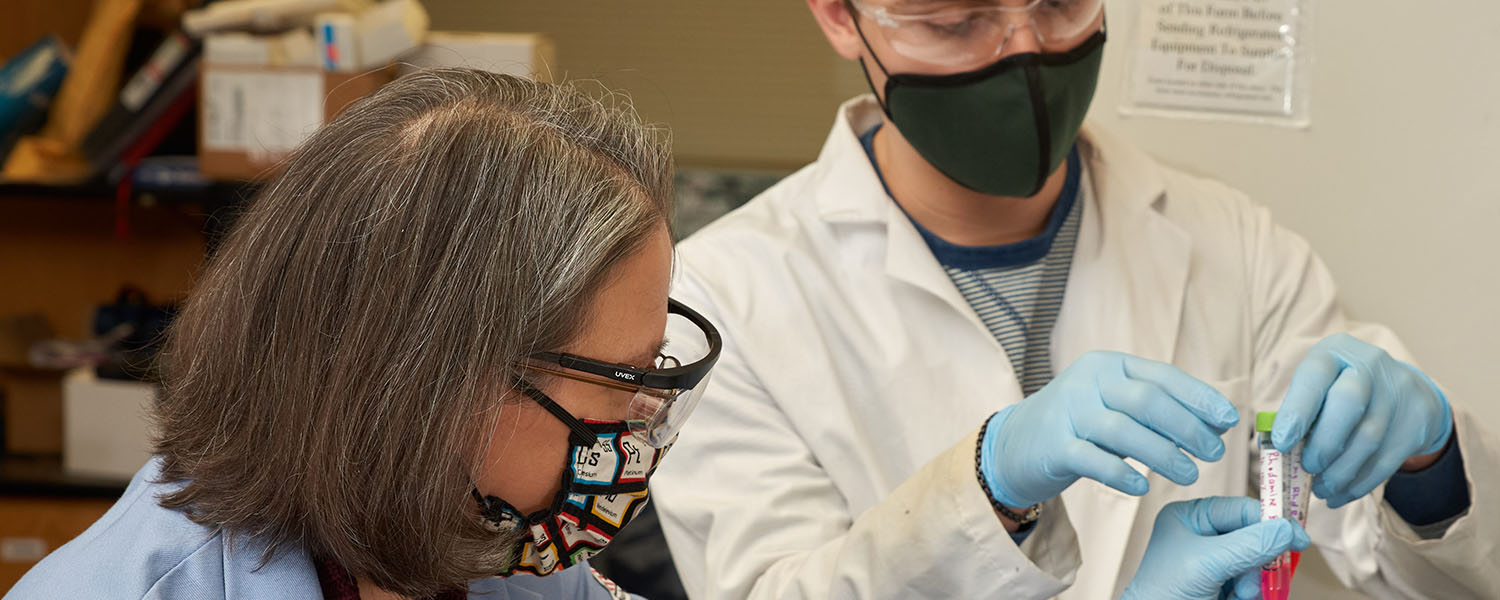 Woman and man in lab with vials of colored liquid.