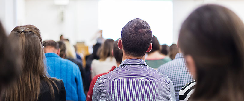 Backs of people's heads in a seminar or meeting setting.