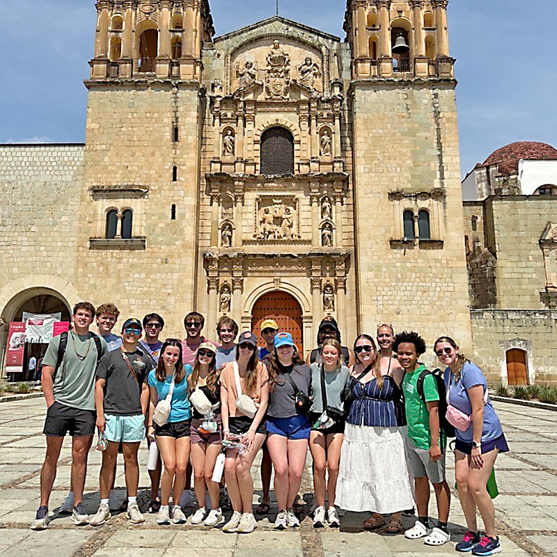 Group of people in front of a yellow brick building.