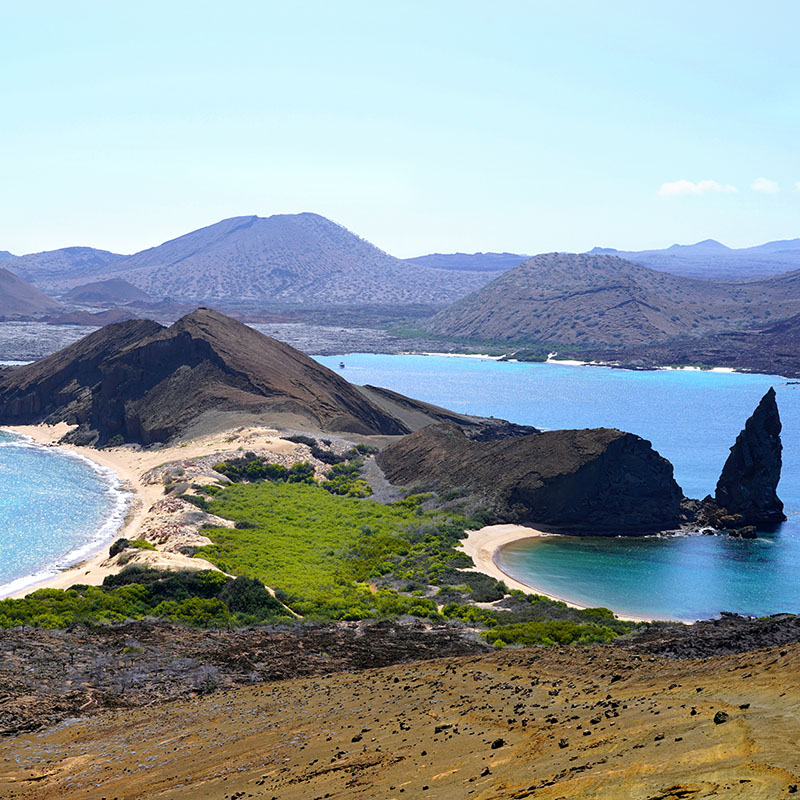 Body of water surrounded by mountains, with a grassy patch in the middle.