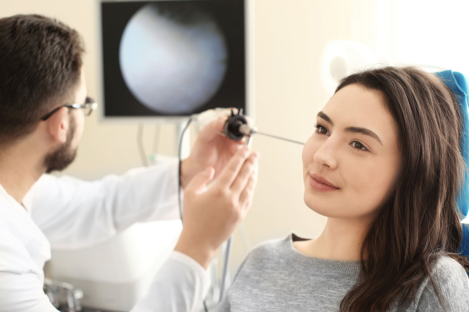 Audiologist examining patient's ear.