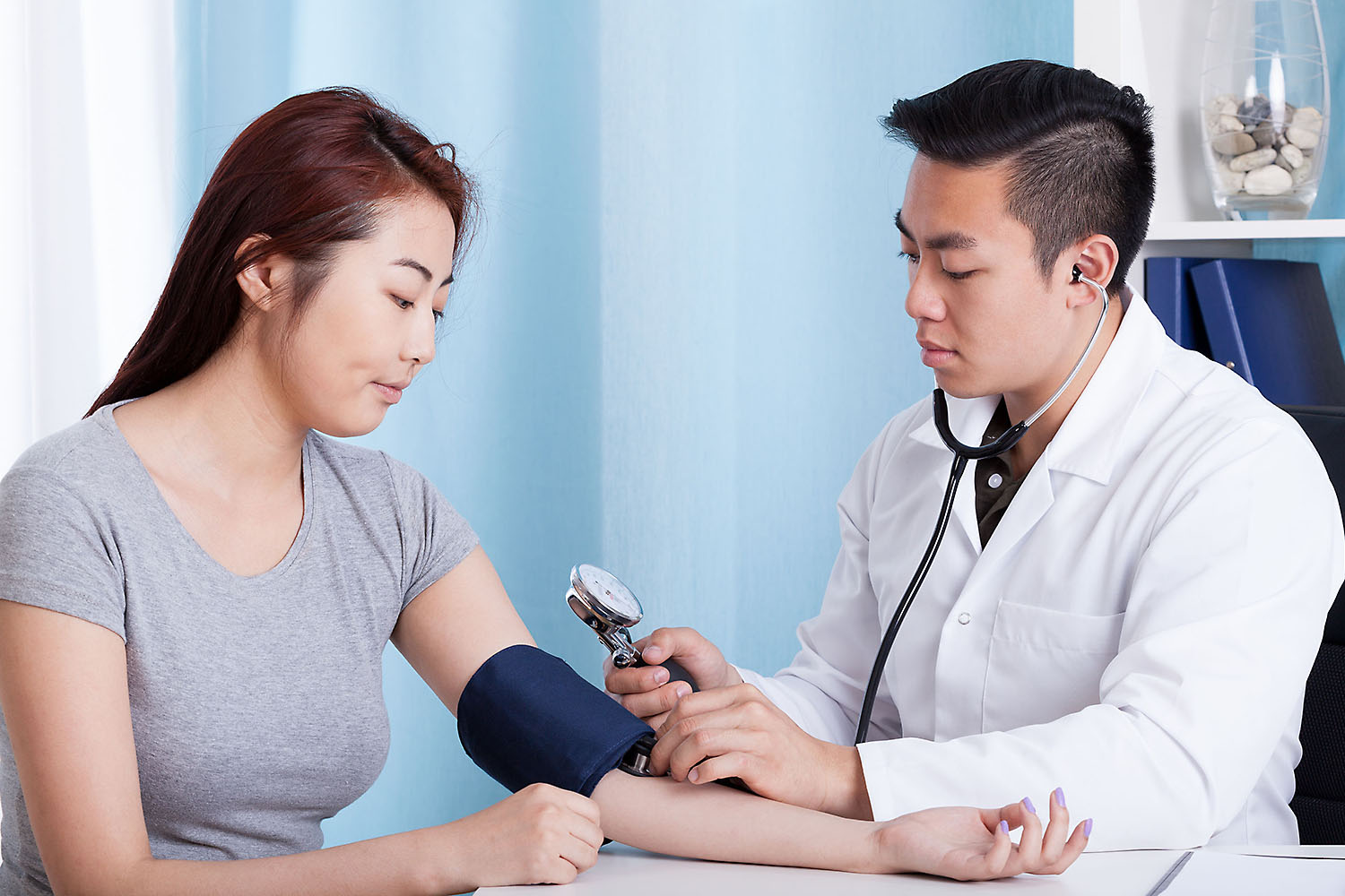 Physician's assistant with patient taking blood pressure.