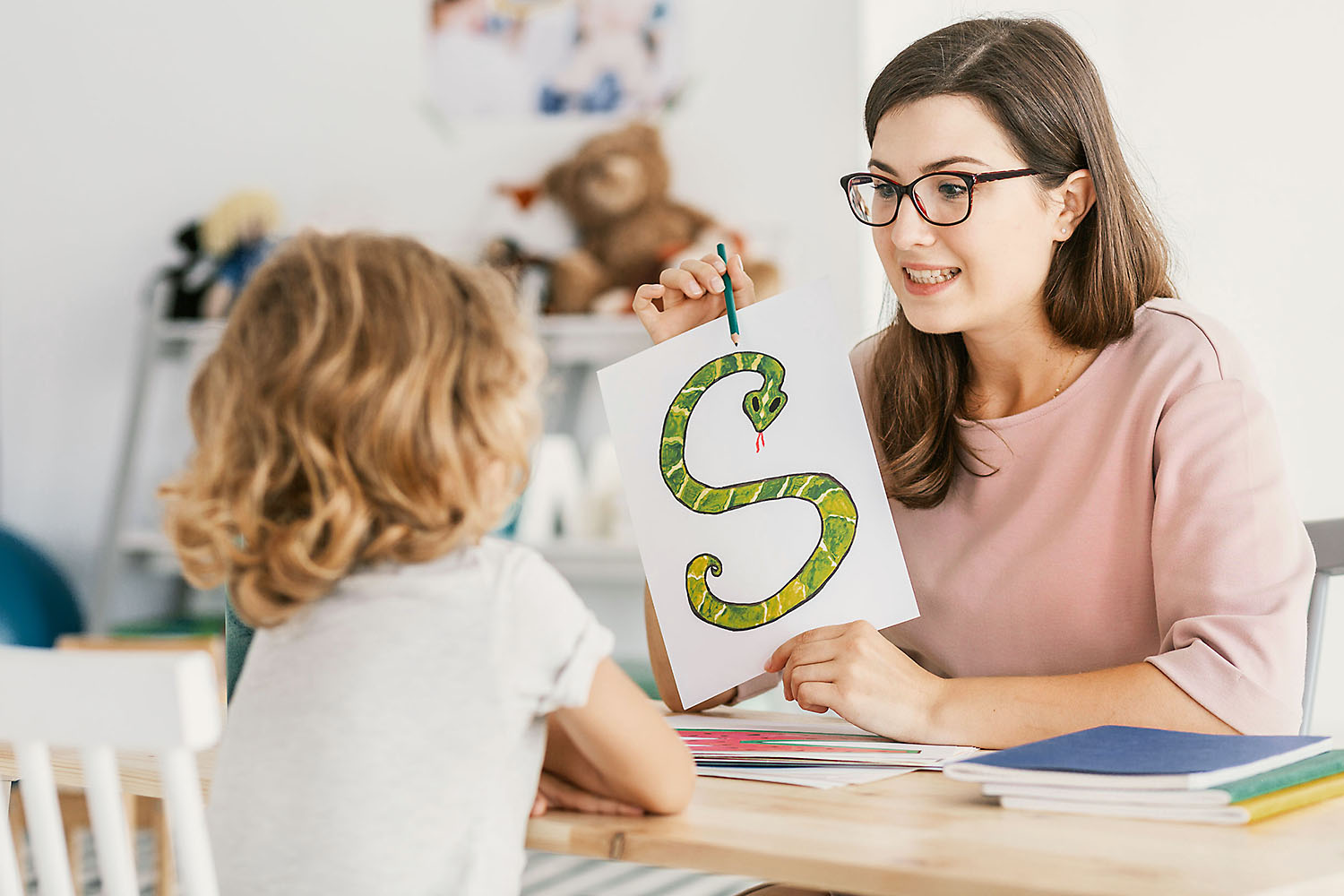 Speech therapist holding sign with letter "S" for child.