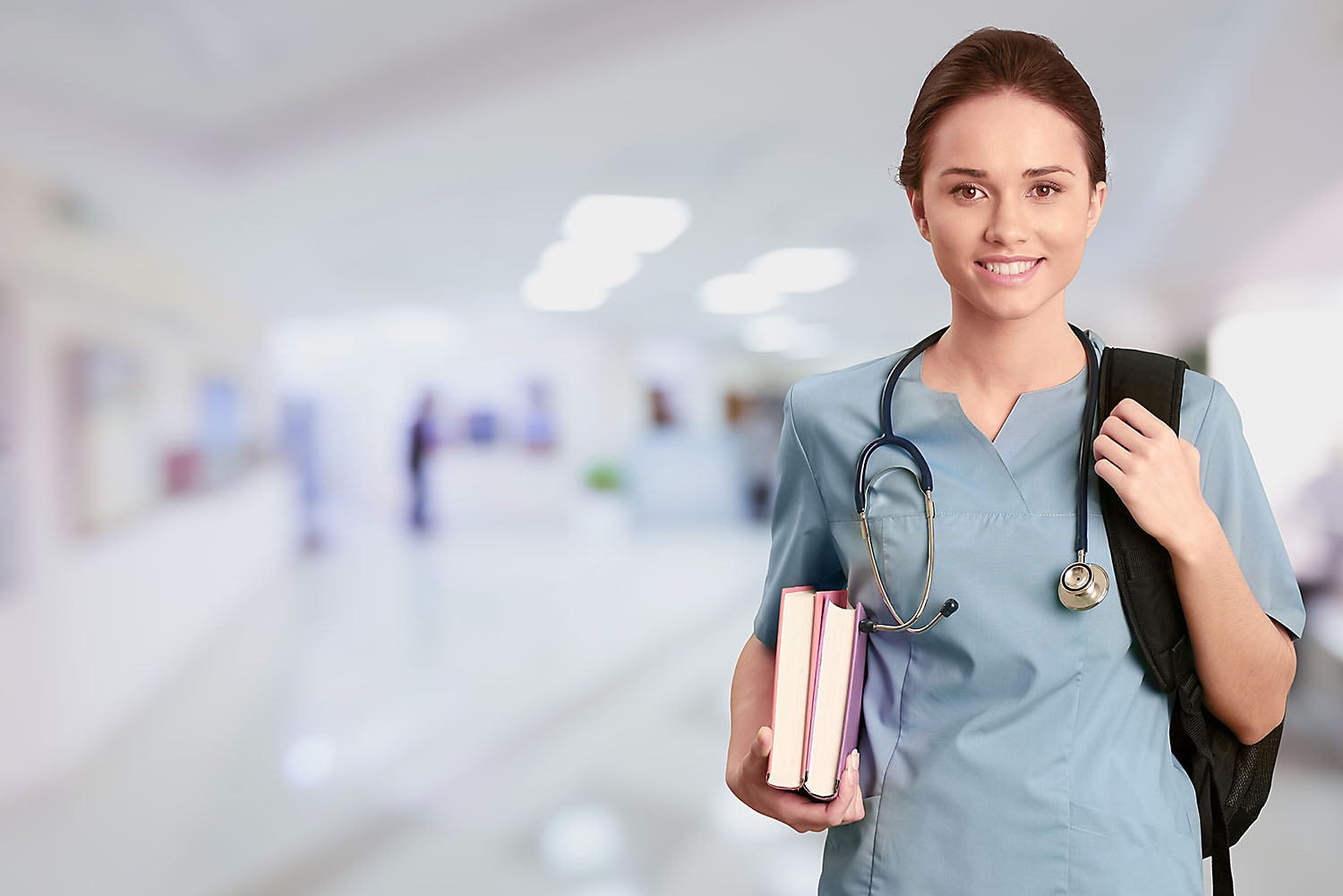 Student in nursing uniform with textbooks.