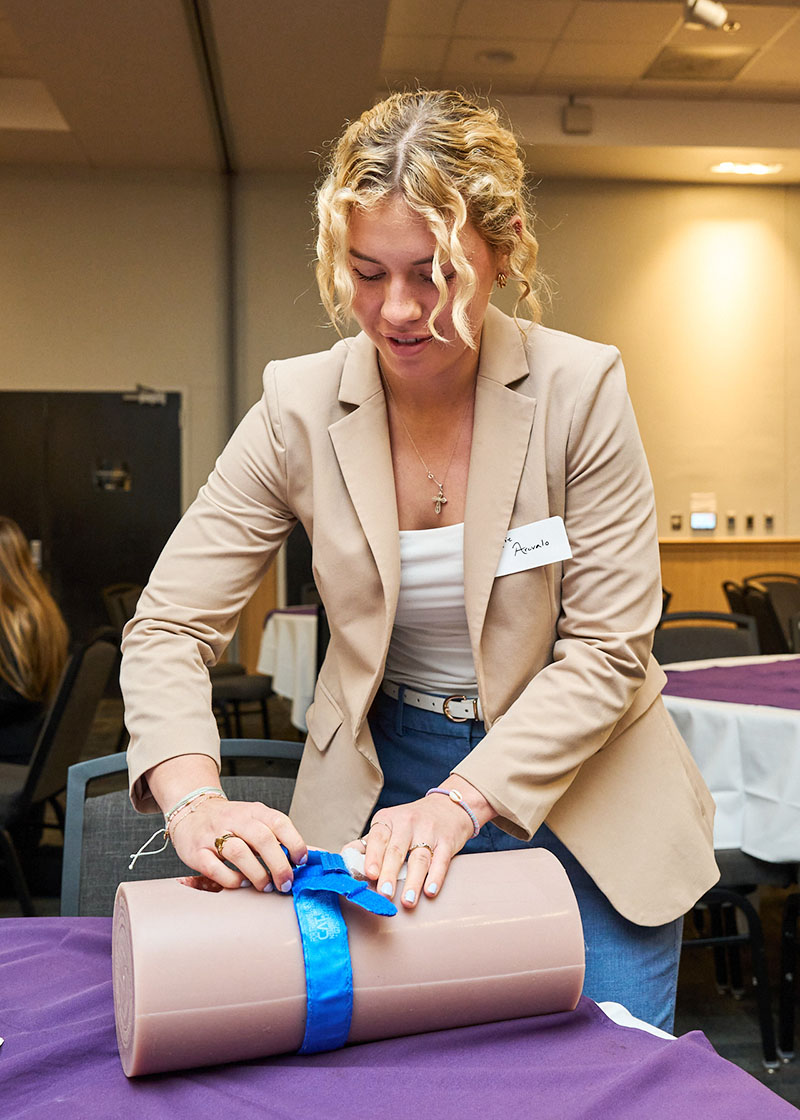 Woman practicing wound care with gauze on a dummy limb.
