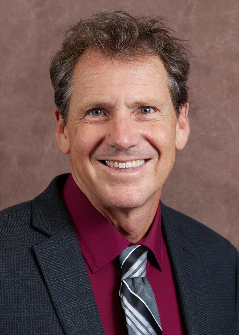 Headshot of Colin Gallagher on brown background.