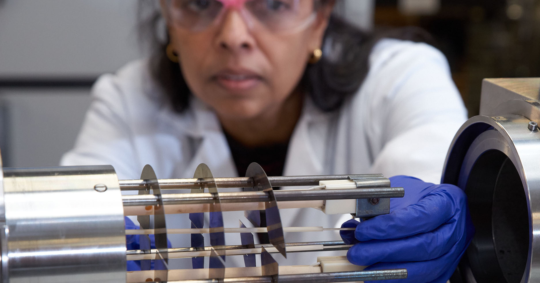 Woman, blurred, examining a machine in a lab.
