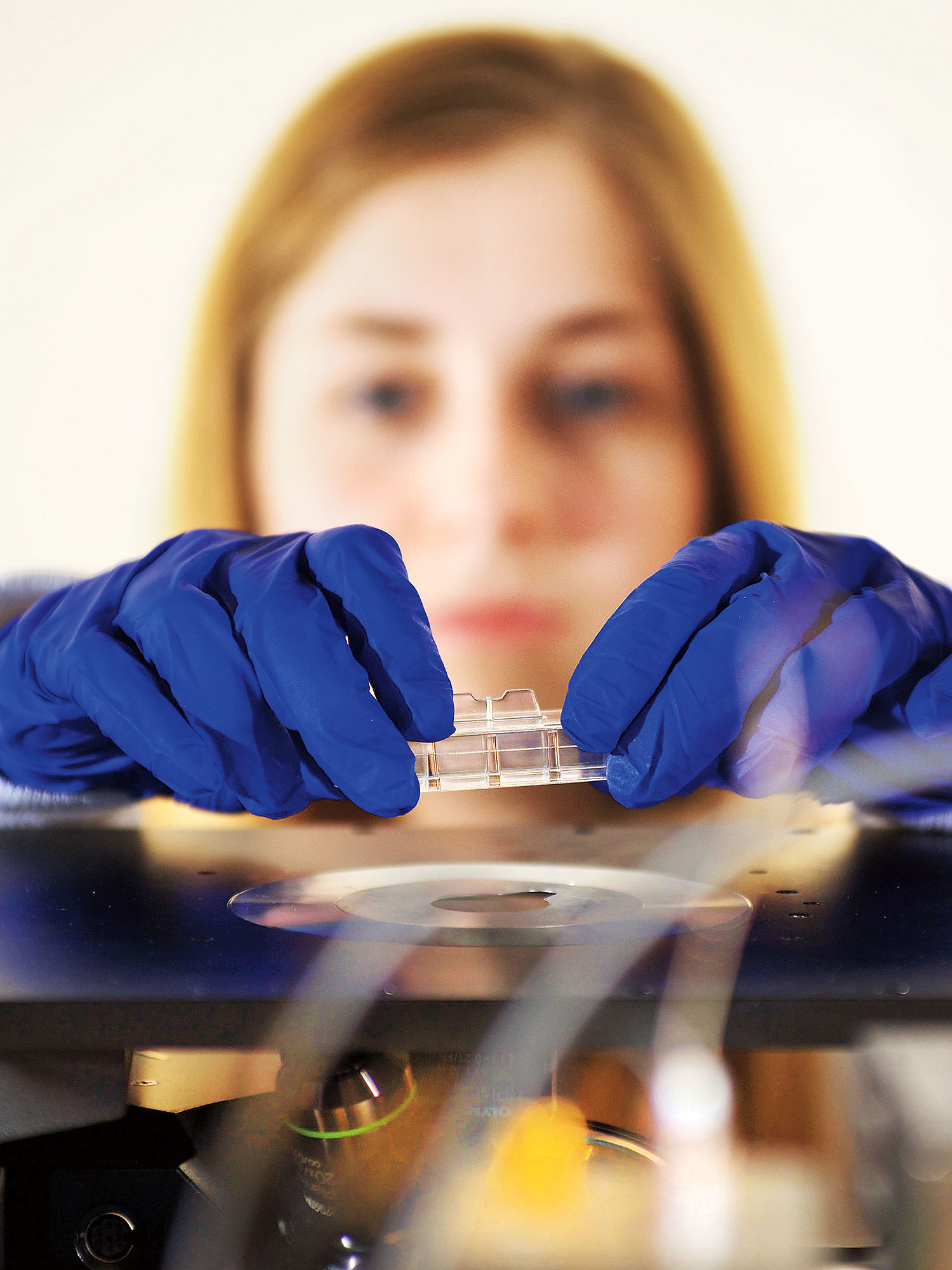 Student in lab placing slide on microscope