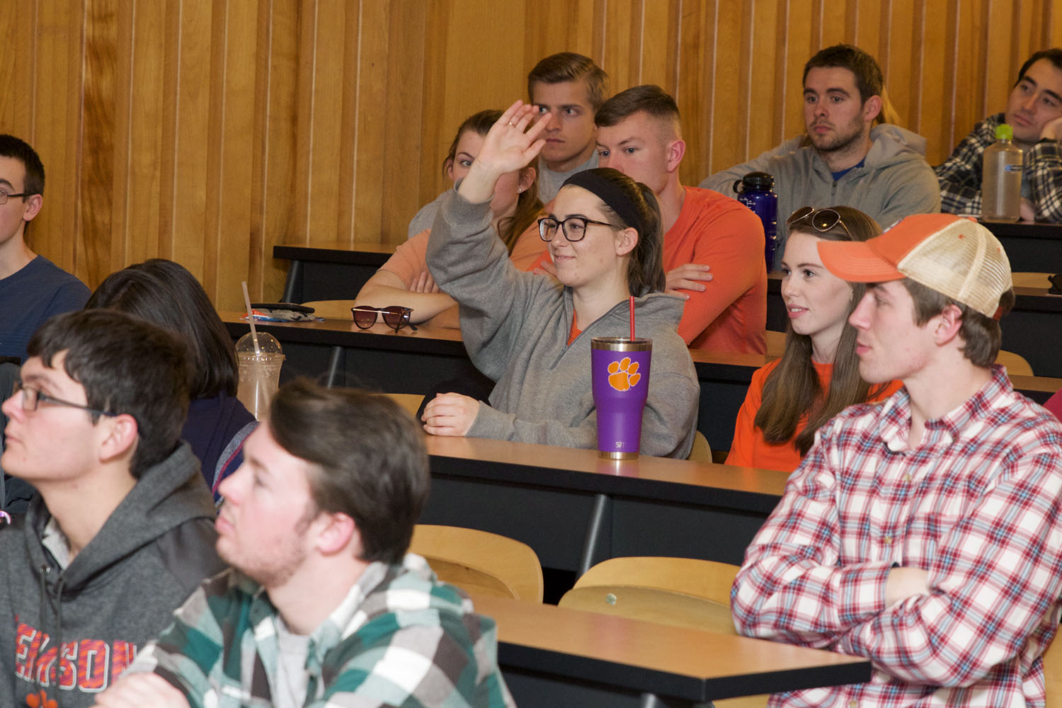 Students in a seminar classroom, with one girl raising her hand.